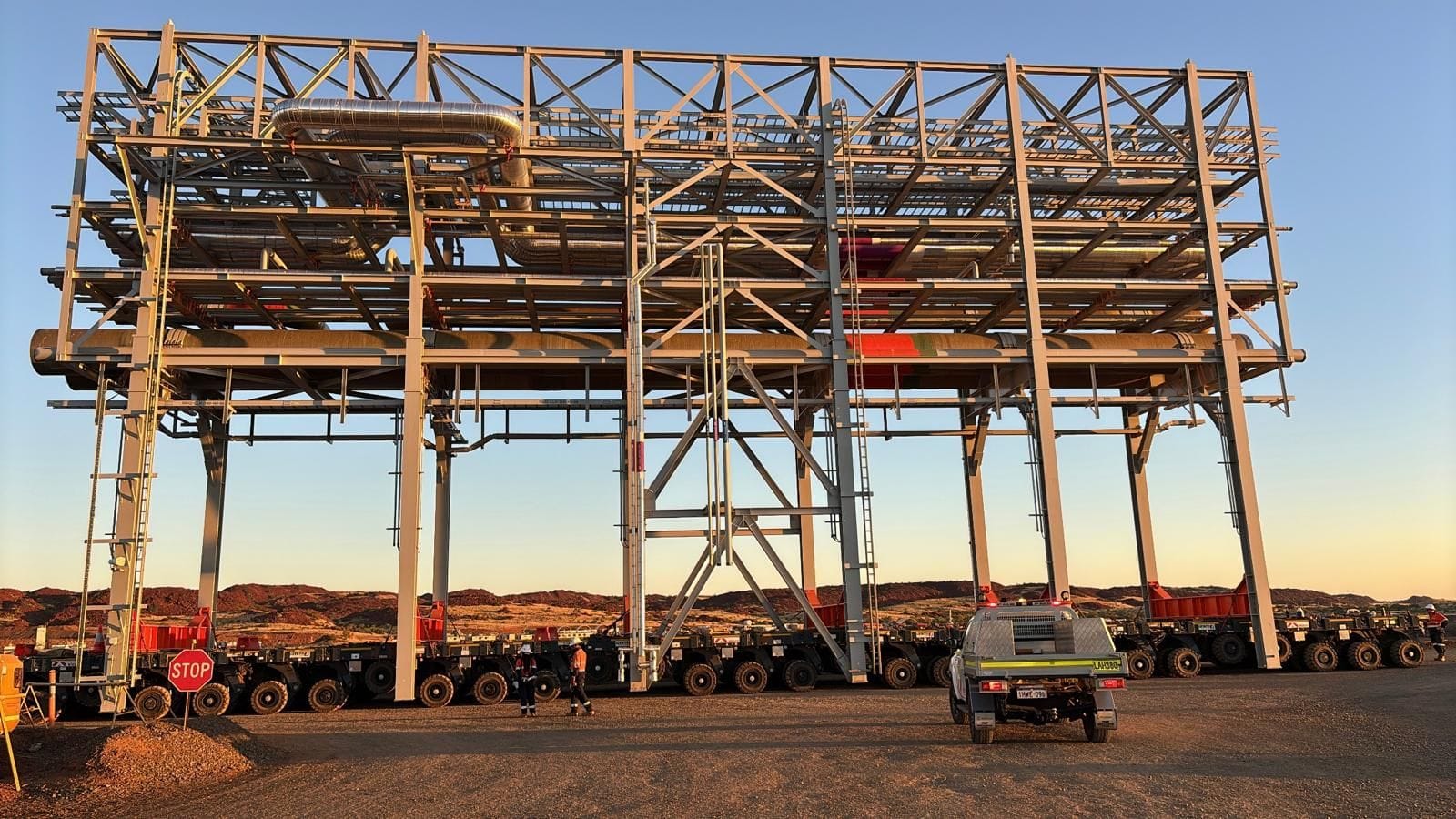 Steel pipe-rack modules on self-propelled transporters at golden hour, Karratha